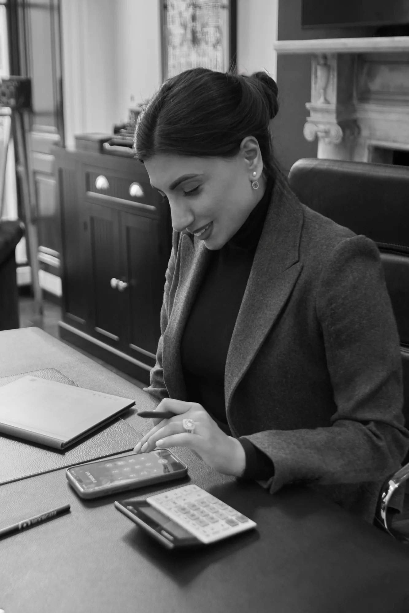 Amna Zaidi working through figures at a desk, in black and white